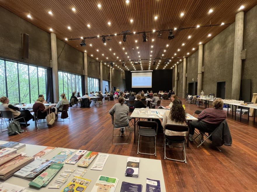 De zaal met werktafels, met vooraan een tafel vol folders.