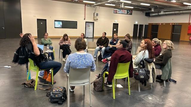Een groep deelnemers in gesprek in een kring van stoelen.